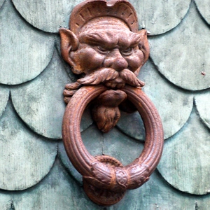 Heurtoir représentant un eprsonnage moustachu tenant un anneau en bouchesur paroi en ardoises - France  - collection de photos clin d'oeil, catégorie portes